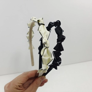 Détail de serre-têtes à nœud plissé avec surpiqûres contrastées en crème et noir