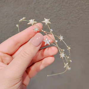 Detailed shot of golden star headband with pearls and rhinestones held in hand