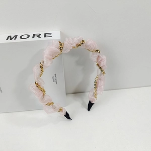 Detailaufnahme von rosa Organza-Haarreif mit Goldkette und dunklen Straßsteinen
