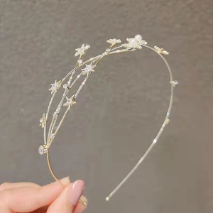 Detail of a golden star headband with sparkling rhinestones and white pearls