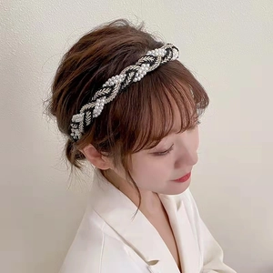 Detail of twisted woven headband with white pearls and silver thread on a female model