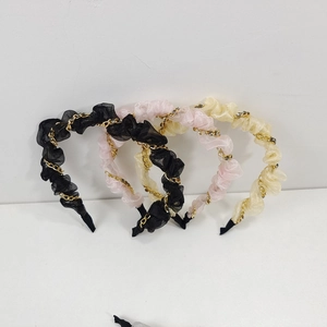 Detail von Organza-Haarbändern mit Goldketten und Strass in Schwarz, Rosa und Beige