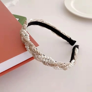Elegant woven pearl headband with gold thread accents on red book background