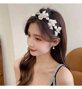 Détail d'un serre-tête en satin blanc avec cœur argenté et boucles d'oreilles en perles chic