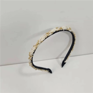 Close-up of black and white woven headband with gold beads and white pearls decoration