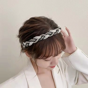 Detail of woven black and white headband with pearls and silver leaf accents on model