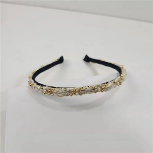 Detailed view of beige woven headband with white pearls and gold beads texture