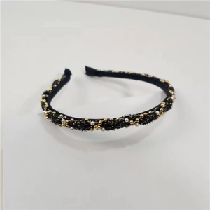 Macro detail of French retro headband with gold beads and white faux pearls on black fabric