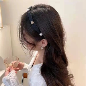 Detailed view of an elegant black headband with delicate pearls and crystals on a model