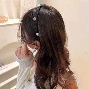 Side view of elegant mesh bow headband with pearls and rhinestones on black satin