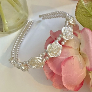 Detailed view of elegant double-layered faux pearl headband with white resin roses