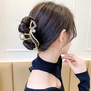 Détail d'une élégante pince à cheveux renard doré avec perle sur cheveux ondulés