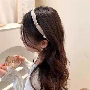 Elegant beige fabric headband detail with pearls and rhinestones shown on a model