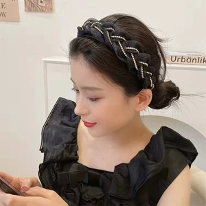 Vista laterale di un cerchietto nero intrecciato con strass indossato da una modella