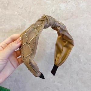 Detail of champagne satin knotted headband with multi-row rhinestone wavy embellishments
