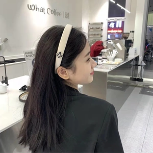 Détail d'un serre-tête en cuir crème avec fleur de camélia et perle porté par un mannequin