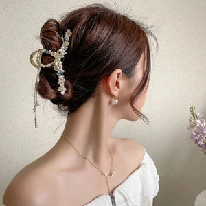 Dettaglio di un fermaglio per capelli in metallo dorato con perline e nappe eleganti