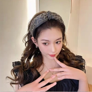 Detail view of dark grey rhinestone headband with shimmering knot design on female model