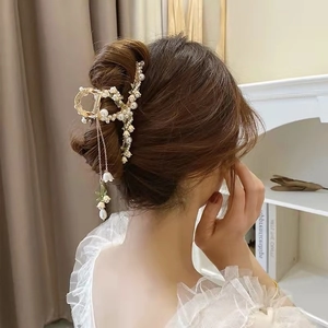 Dettaglio di un fermaglio per capelli dorato con mughetto e perle su un'acconciatura