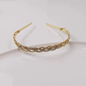 Detail of a gold braided metal headband on a white ceramic plate with a minimalist aesthetic