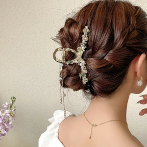 Dettaglio del fermaglio per capelli dorato con perle, stelle marine e nappa decorativa