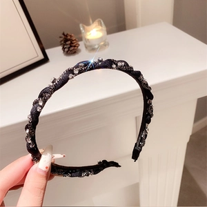 Dettaglio di un cerchietto in tessuto intrecciato nero con strass brillanti