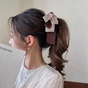 Detail view of a large bow hair clip with layered brown satin and champagne glitter fabric