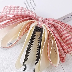 Détail du clip banane avec nœud pied-de-poule rose montrant la texture du ruban satin
