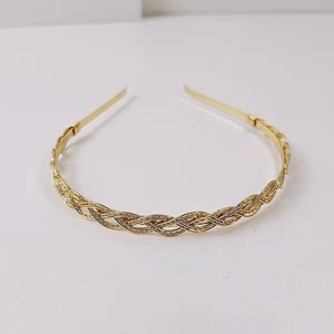 Close-up of golden alloy headband featuring a classic woven texture on a white background