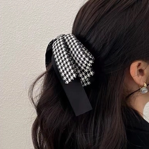 Détail d'une pince à cheveux avec nœud pied-de-poule portée par un mannequin
