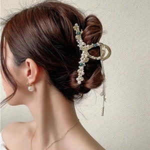 Dettaglio di un fermaglio per capelli a conchiglia dorata con lunghe nappe metalliche