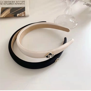 Détails des serre-têtes camélia noir et crème avec perles et finitions métalliques