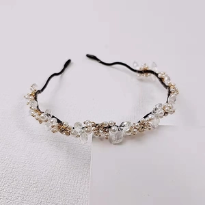 Détail d'un serre-tête artisanal avec perles blanches et cristaux clairs sur fil fin