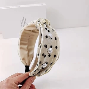 Close-up of beige polka dot fabric headband with white square pearls and knotted top