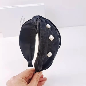 Detail of black polka dot headband featuring a twisted knot design and white pearl accents