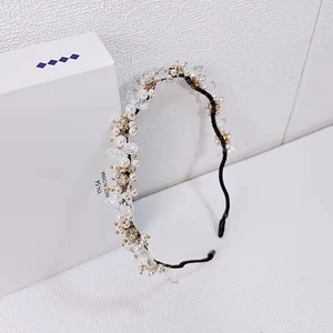 Détail d'un serre-tête élégant en perles blanches et cristal avec accents dorés