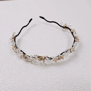 Détail d'un serre-tête fait main avec perles blanches, cristaux et accents dorés
