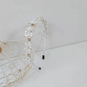 Dettaglio di cerchietto con fiori bianchi e cristalli su un cesto metallico