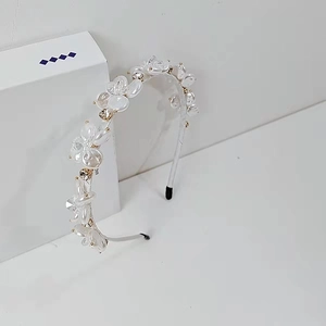 Dettaglio della fascia per capelli con fiori bianchi, perle e cristalli su scatola regalo