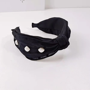 Detail of a black fabric headband with twist knot design and three square pearl embellishments