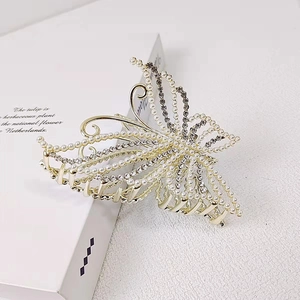 Elegant gold butterfly hair claw clip with pearls and rhinestones on a white book