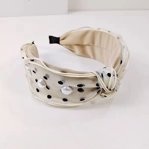 Close-up of champagne polka dot headband with elegant white pearls and top knot detail