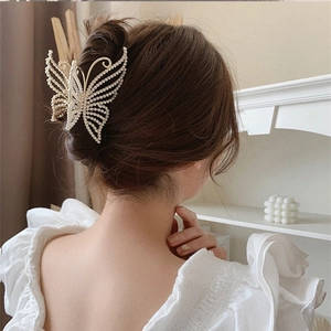 Elegant gold butterfly hair claw with pearls shown on model's updo hairstyle