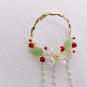 Close-up of golden hair stick with white resin flowers and long pearl tassels