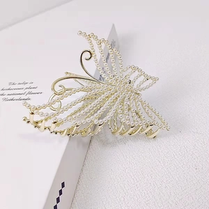 Elegant gold butterfly hair claw clip with inlaid pearls on a minimalist background