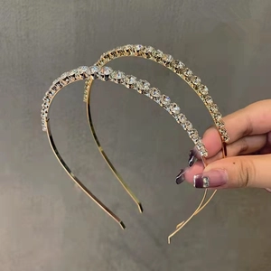 Vue détaillée de deux serre-têtes dorés ornés de strass brillants et structure flexible