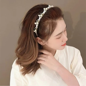 Detailed view of handmade pearl flower headband worn by a model in soft lighting