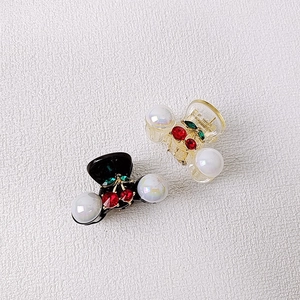 Close-up of cherry hair clips with faux pearls and rhinestones on a white texture