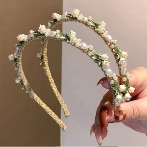Detail of handmade lily of the valley floral headbands with white pearls and gold base