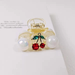 French vintage mini cherry hair claw clip with pearls and red rhinestones on white book